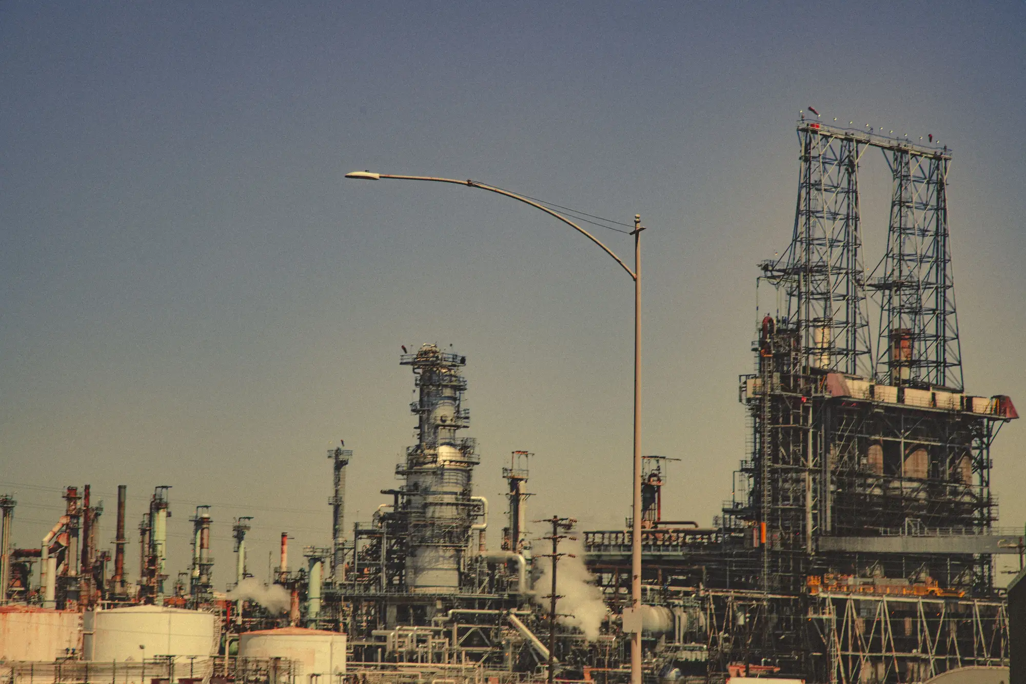 Refinery process units and a steel-framed structure against a clear sky